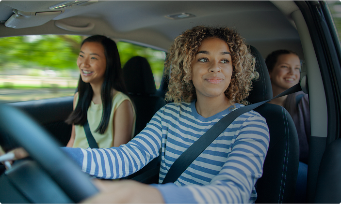 A diverse group of people smiling and holding a 'Drive Aware North Texas' pledge sign